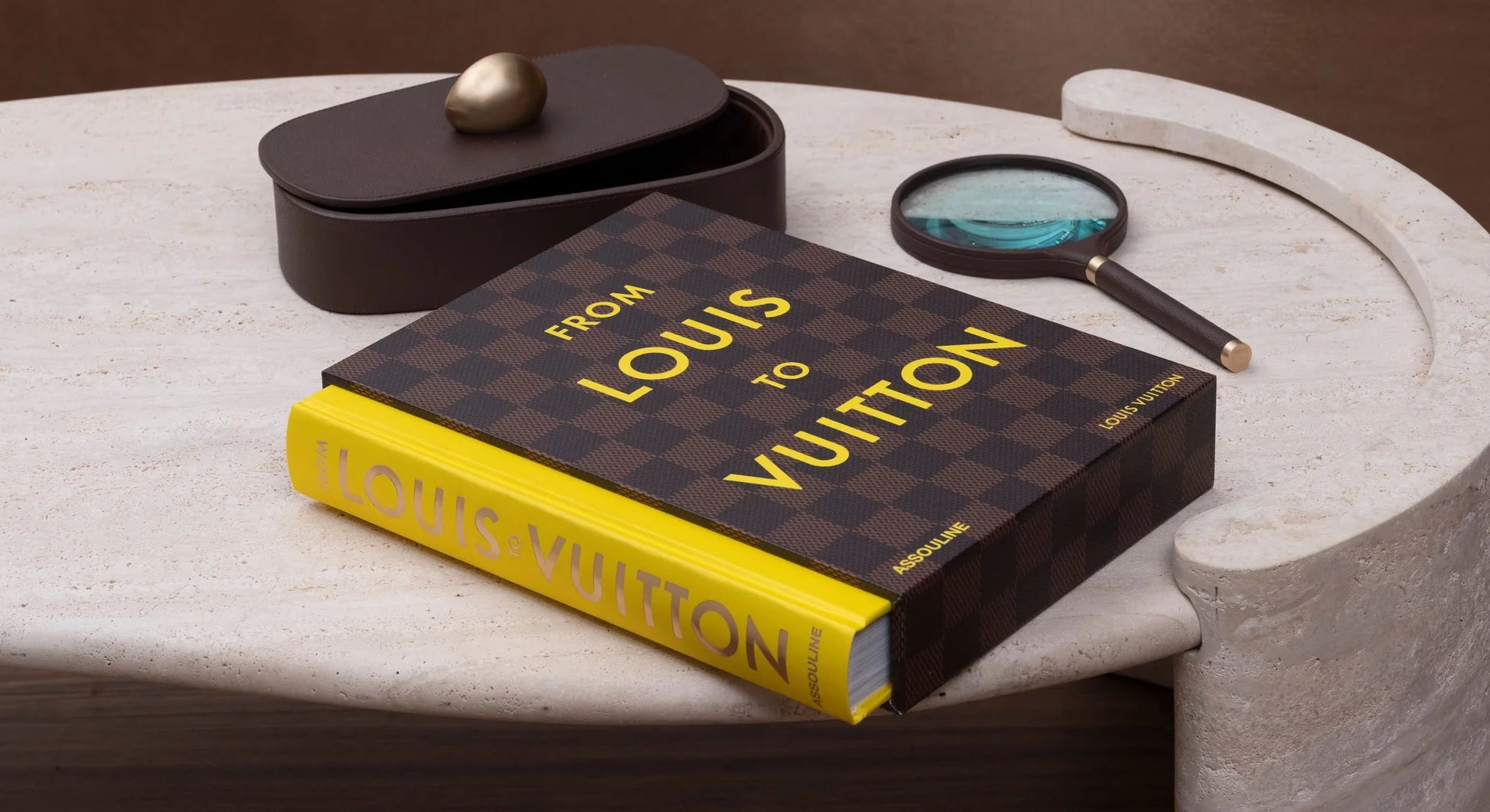 Libro From Louis to Vuitton de Assouline, en ambiente de lujo con lupa y caja decorativa.