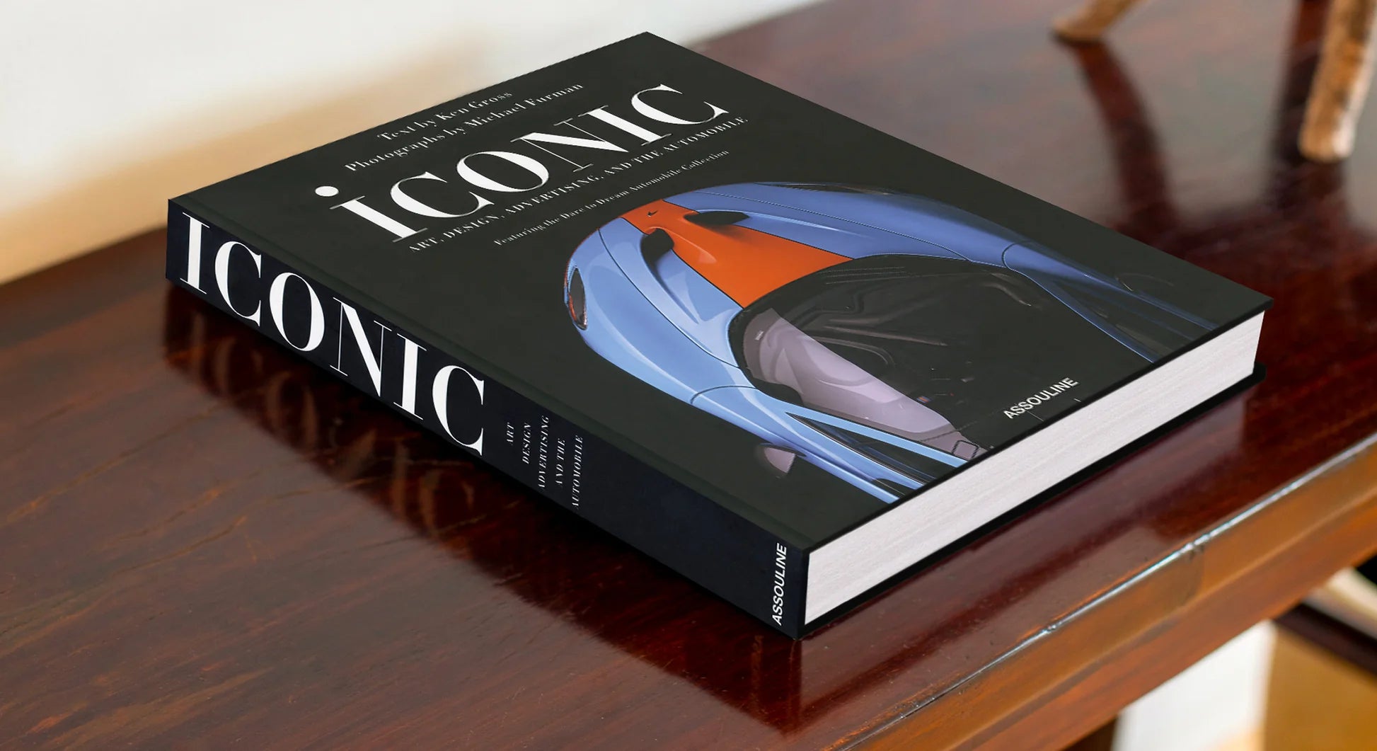 Libro de arte Iconic Assouline sobre una elegante mesa de madera oscura, ideal para decoración de interiores de lujo.