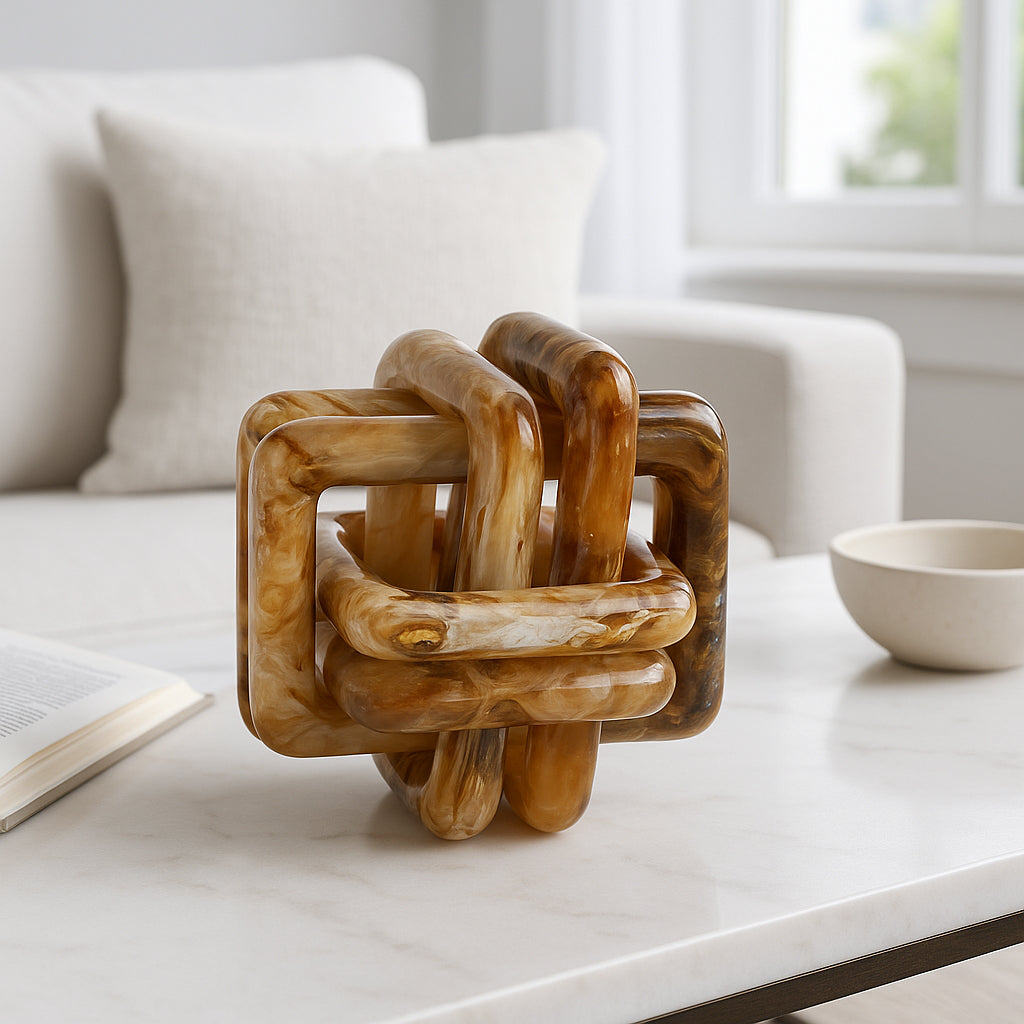 Escultura de nudo marmoleado en mesa de sala, con cojines y tazón, creando ambiente elegante.