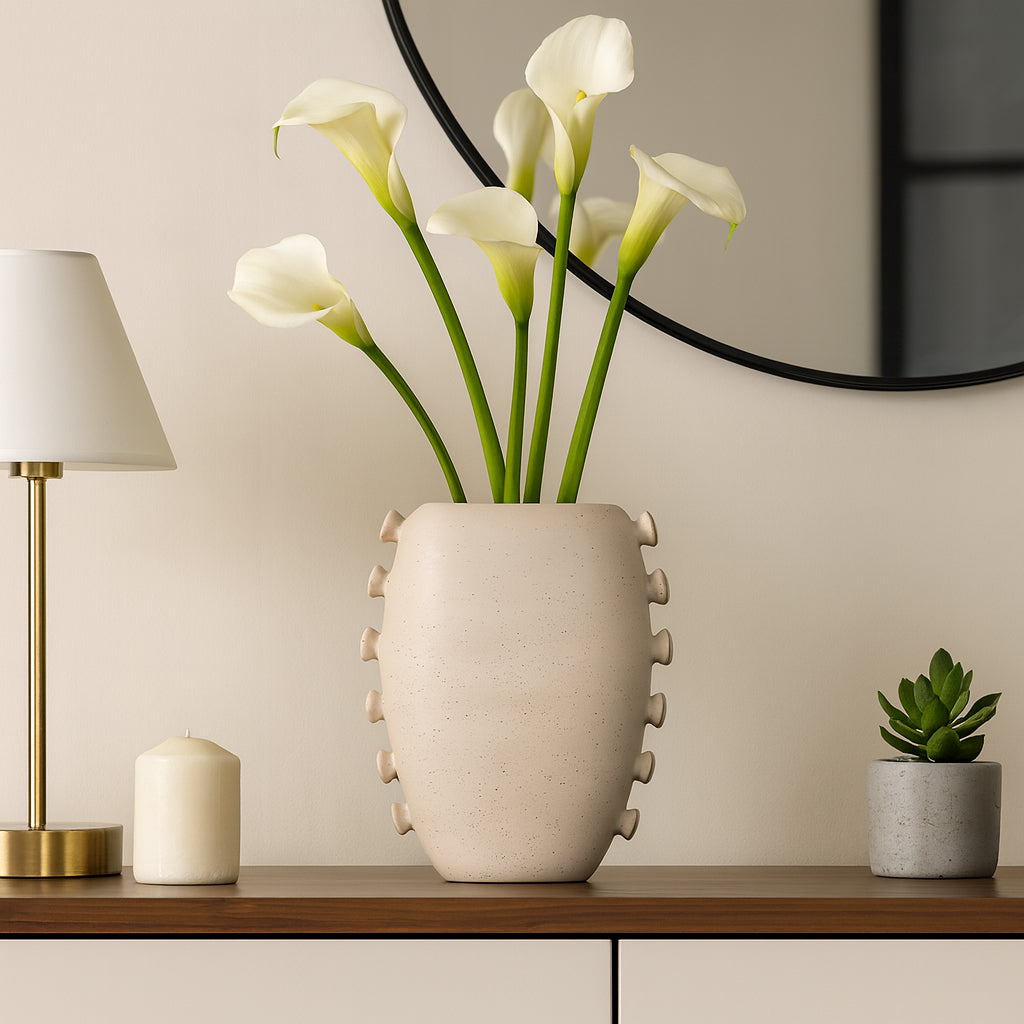 Jarrón cerámico beige en un ambiente de sala elegante con calas blancas y detalles de lujo.