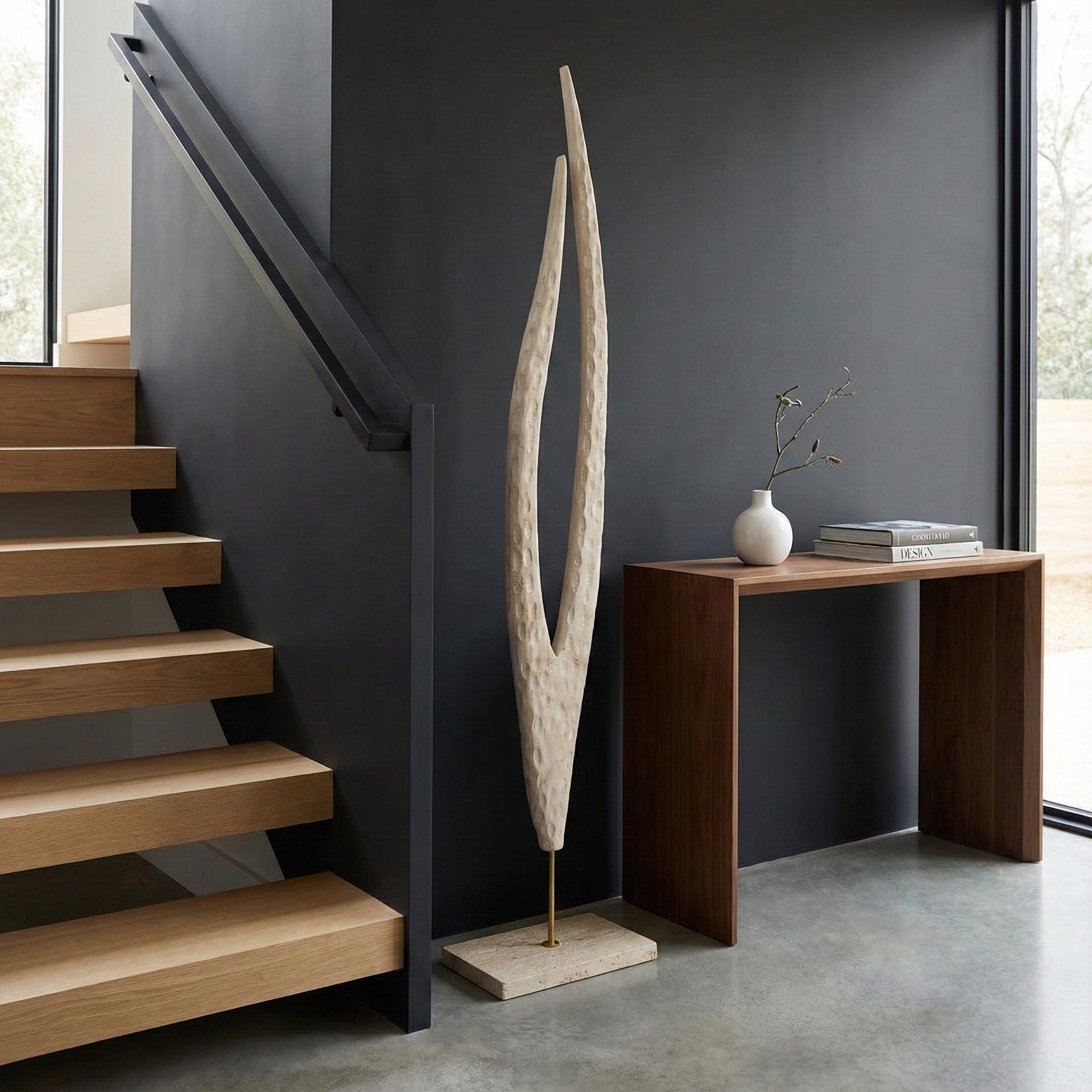 Escultura moderna texturizada en beige claro decorando una entrada elegante con mesa de madera.
