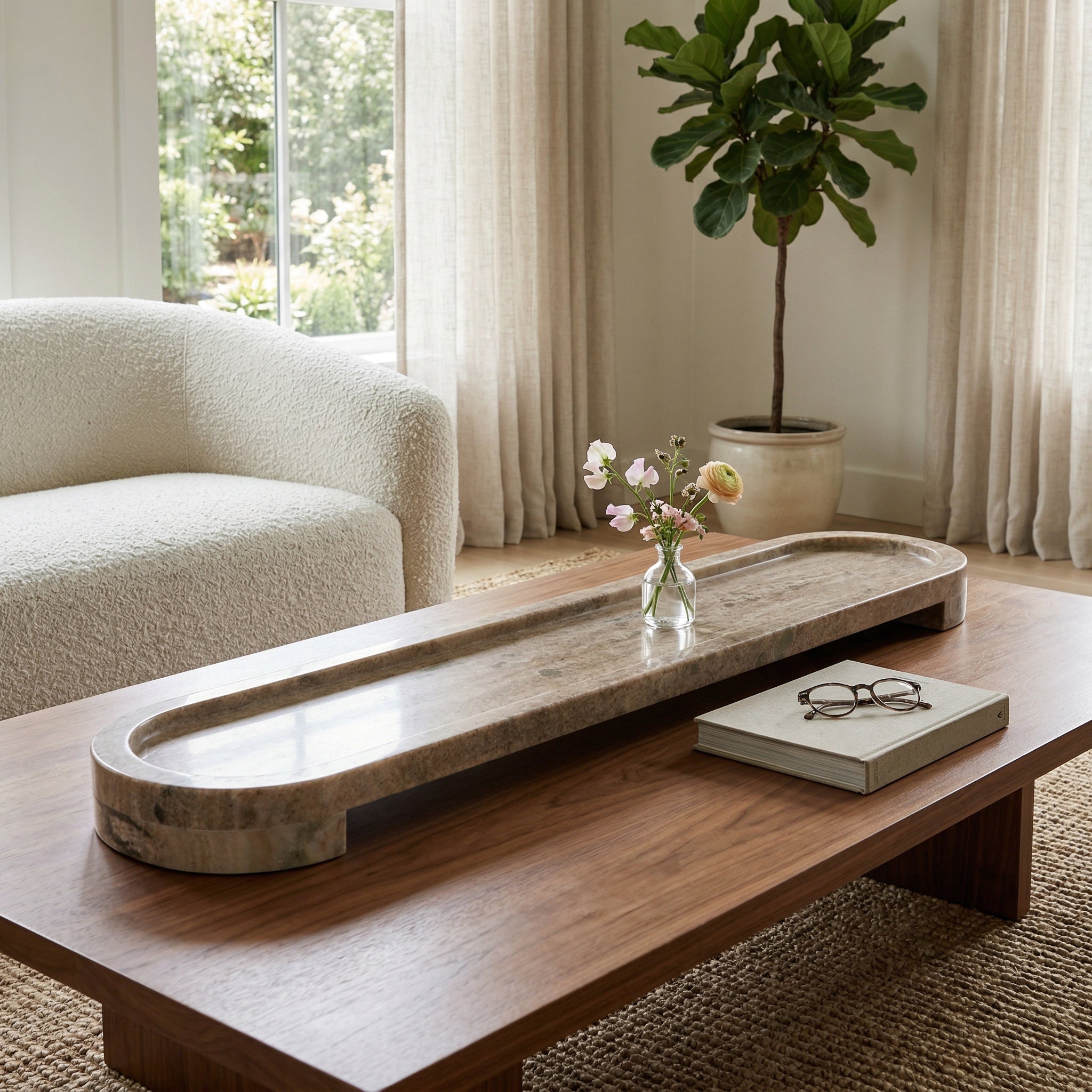 Bandeja de mármol ovalada como centro de mesa en sala moderna con sofá y planta.