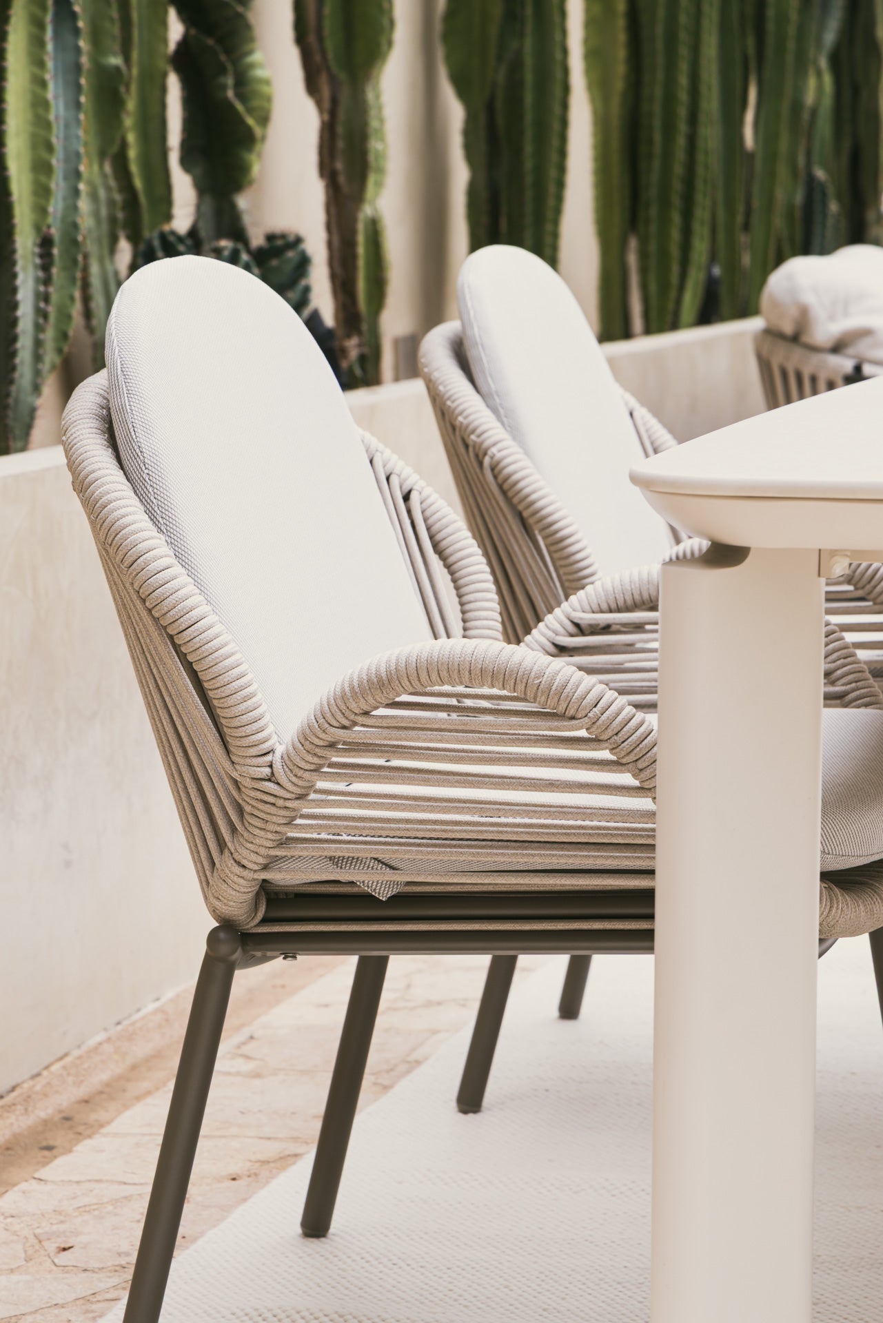 Detalle de silla de exterior con tejido de cuerda acrílica beige y cojines suaves.