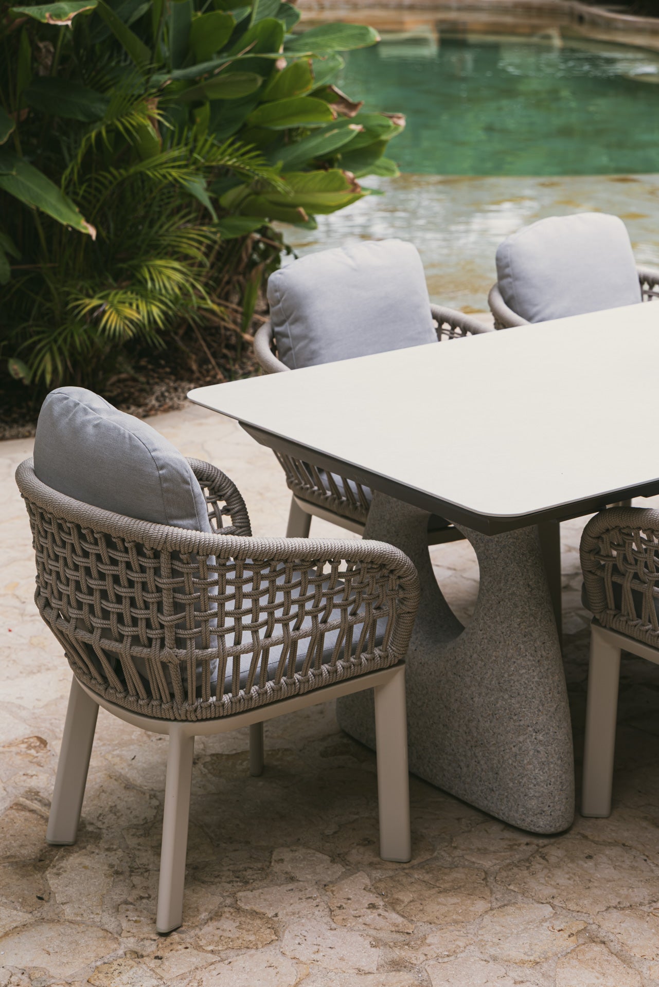 Elegante sillón de jardín y mesa de comedor junto a piscina para ambiente exclusivo.