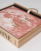 Libro de vino Assouline semi-extraído de su caja de madera, revelando la tapa con ilustración clásica.