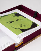 Página interior del libro 'Andy Warhol' de Assouline con un retrato icónico del artista en tonos verdes brillantes, dentro de su estuche.