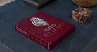 Libro decorativo Assouline The Impossible Collection of Watches sobre una mesa oscura, junto a accesorios de lujo.