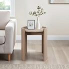 Mesa auxiliar moderna en madera y piedra junto a un sofá beige, decorada con un marco y un jarrón en una sala elegante.