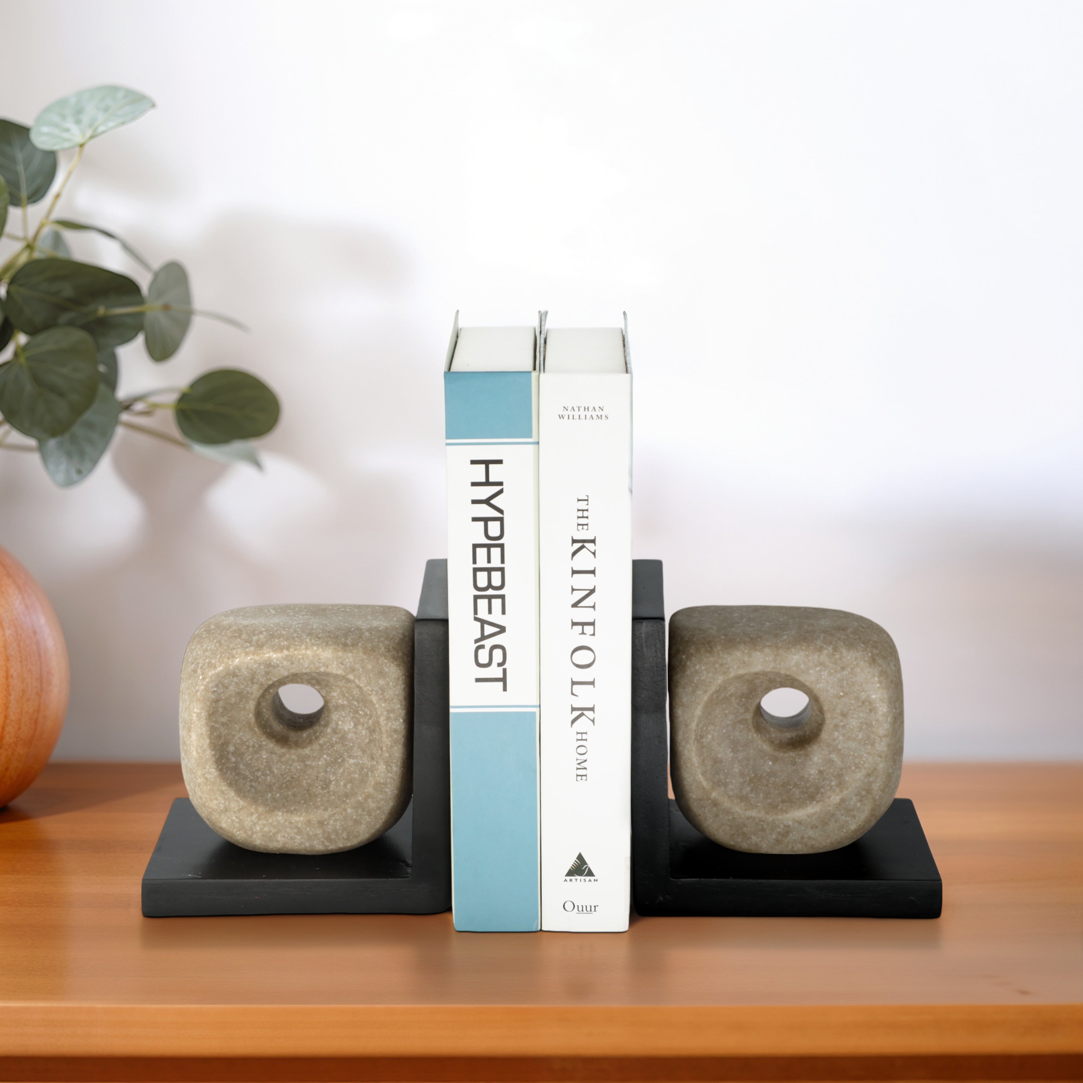 Sujetalibros decorativos en piedra sosteniendo libros "Hypebeast" y "Kinfolk Home" en escritorio de madera.