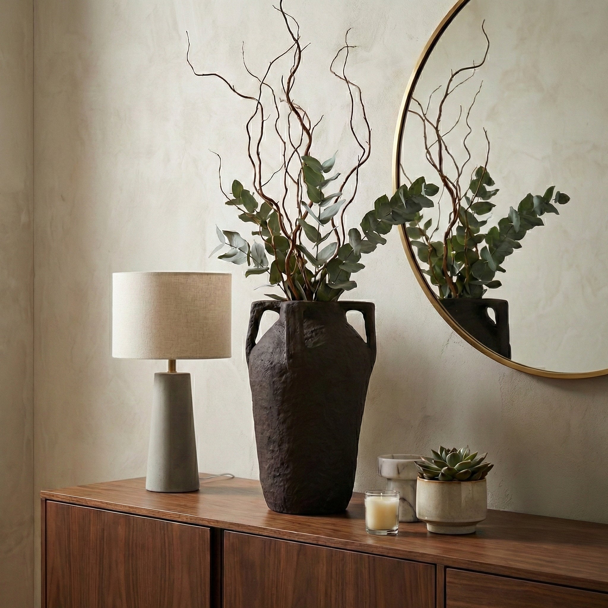 Jarrón alto decorativo en sala, con ramas secas y eucalipto, creando un ambiente sofisticado.