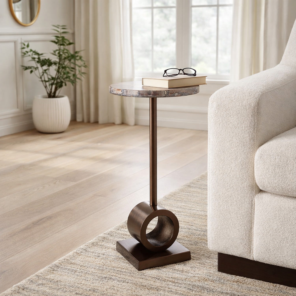 Mesa auxiliar moderna en sala de estar, con tapa mármol y base bronce, junto a un sofá beige claro.