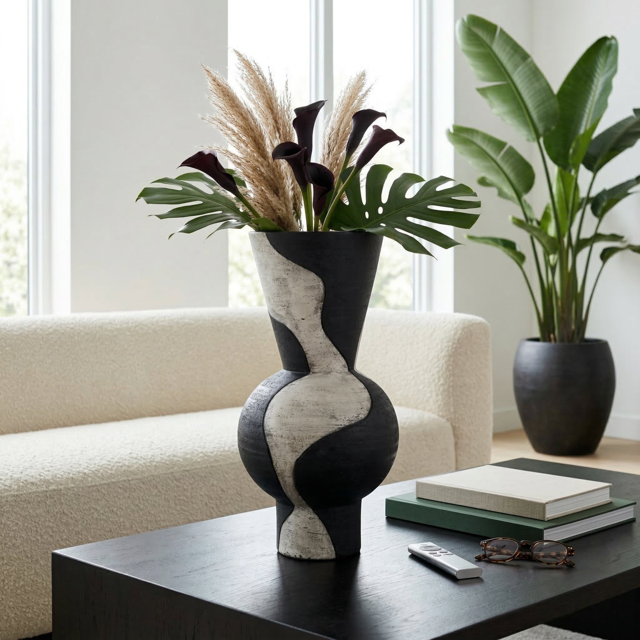 Jarrón decorativo negro y blanco en sala moderna, sobre mesa de centro con flores secas