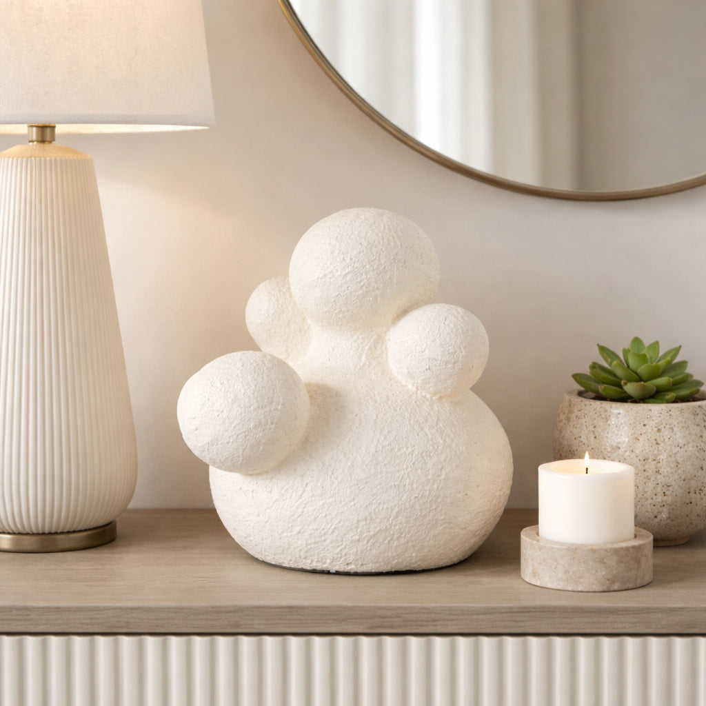 Escultura blanca moderna en cómoda con lámpara, espejo y vela en un hogar elegante