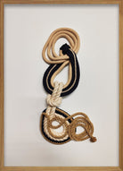 Cuadro de Vilá Decoración con marco de madera, fondo de tela blanca y diseño abstracto con cuerdas de tela en tonos beige, azul marino y dorado.