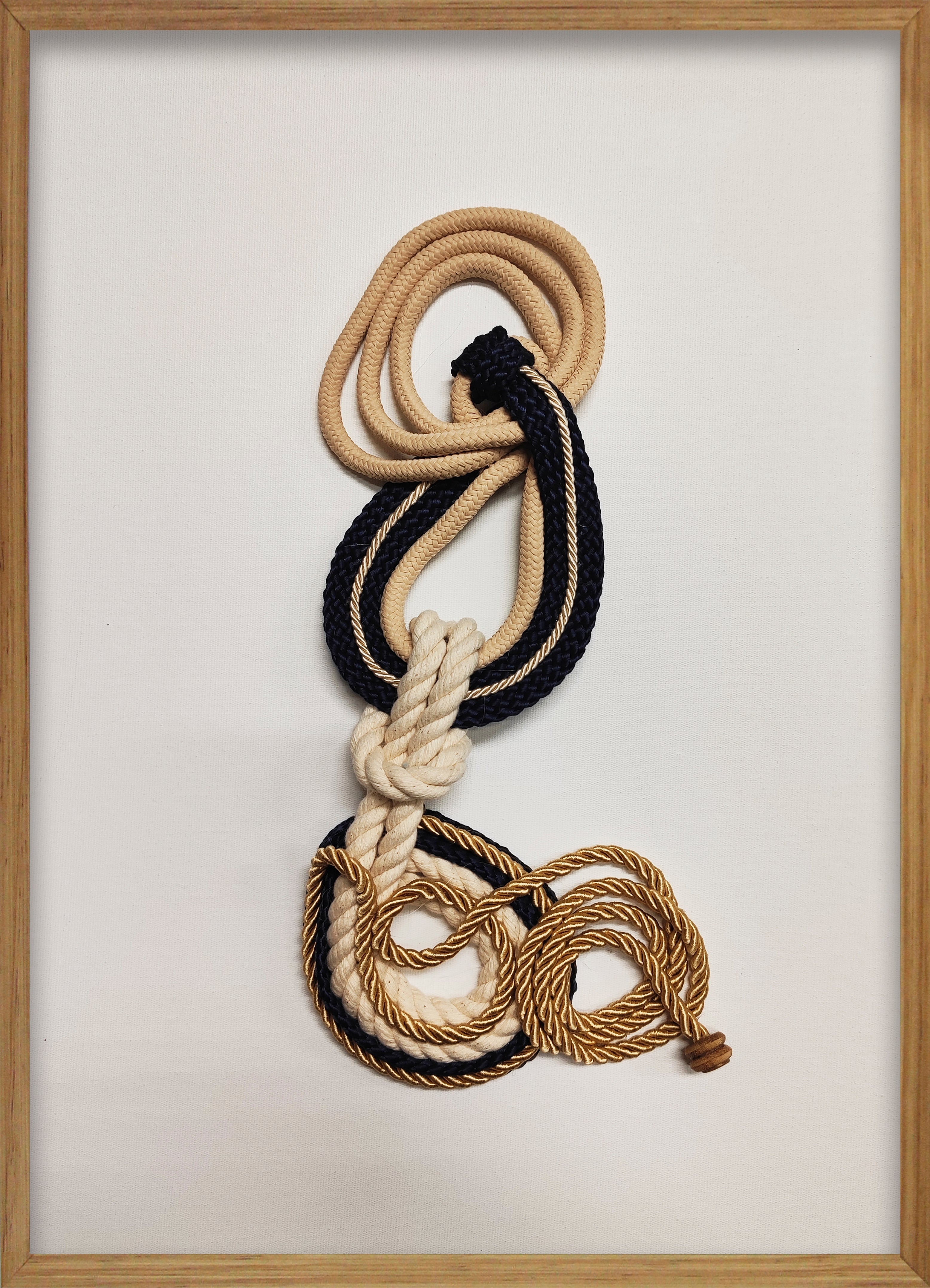 Cuadro de Vilá Decoración con marco de madera, fondo de tela blanca y diseño abstracto con cuerdas de tela en tonos beige, azul marino y dorado.