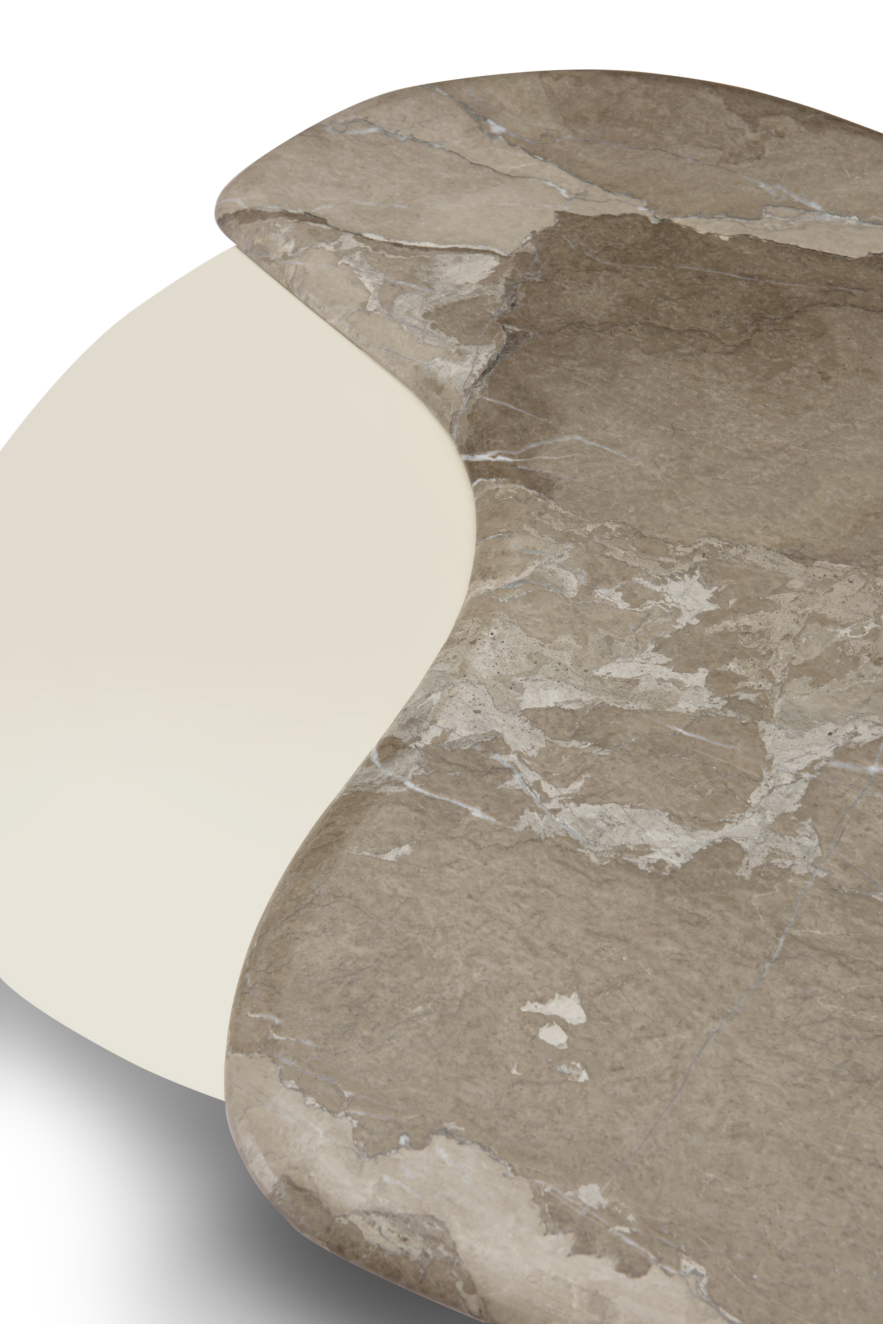 Detalle de la superficie de mesa de centro, combinando mármol natural y elemento curvo en color crema.