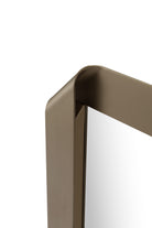 Detalle cercano del elegante marco curvo y acabado premium del espejo de pared en tono bronce.