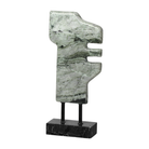 Escultura abstracta de mármol verde con vetas naturales sobre base negra, exhibiendo elegancia y