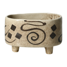 Jarrón decorativo de cerámica beige con patas y diseño abstracto étnico en tonos oscuros.