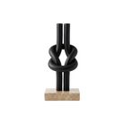 Escultura decorativa abstracta de nudo en negro mate sobre base de mármol beige, pieza de lujo para interiores modernos.