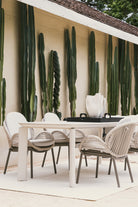 Mesa de comedor exterior con sillas de lujo, ideal para patio o terraza, rodeada de cactus altos.